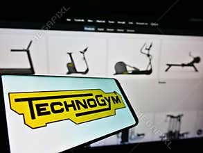 Smartphone with logo of Italian fitness equipment company Technogym S.p.A. on screen in front of business website.
