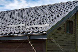 Metal roof construction on a wooden house. Rain gutter.