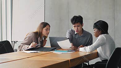 Three business people examining financial data in document sitting at table. Colleagues team brainstorming in modern