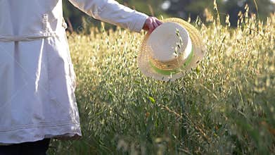 Woman with straw hat in field of oats