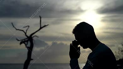 Silhouette of Man pray on sunset and dramatic sky background. Repentance, regret and hope concept