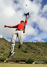 Baseball player jumps to catch a fly ball