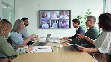 Diverse employees on online conference video call on tv screen in meeting room.