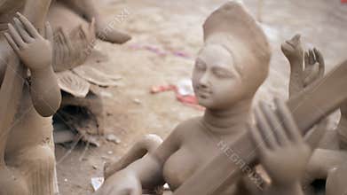 Pan shot of a clay workshop with many statues and a woman preparing an idol