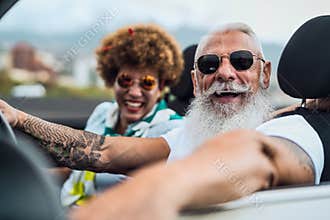 Happy senior couple having fun driving on new convertible car - Mature people enjoying time together during road trip