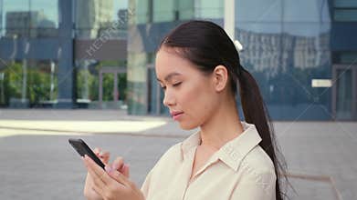 Asian Woman Using Phone Scrolling Reading News Online Standing Outside