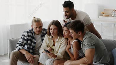 Group Of Young Multiethnic Friends Using Smartphone Together While Relaxing At Home
