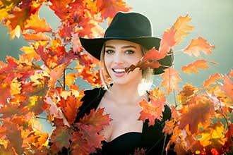Portrait of cheerful young woman with autumn leafs. Autumn woman with yellow maple leaves on golden fall. Happy smiling