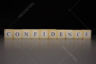 The word CONFIDENCEwritten on wooden cubes isolated on a black background