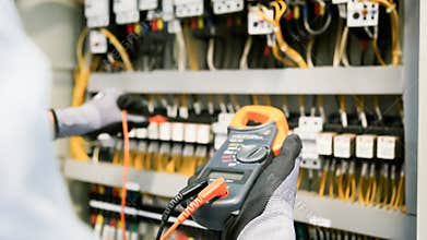 Electrical engineers test electrical installations and wiring on protective relays, measuring them with a multimeter