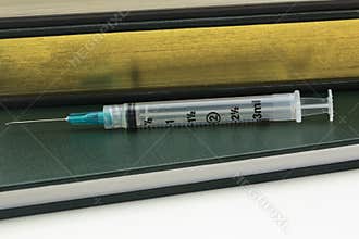 Books and injection needle reflect medical data and research