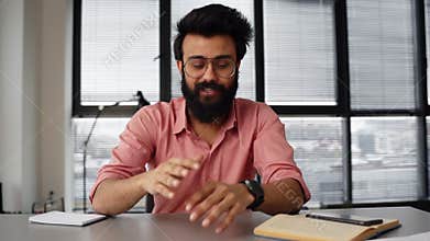 Webcam view of handsome positive Indian businessman talking with colleagues on video call using laptop computer sitting