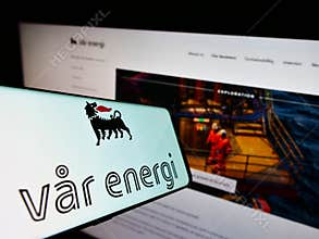 Smartphone with logo of Norwegian oil and gas company Var Energi on screen in front of website.