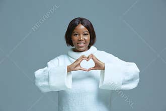 Peace and love. Smiling african american friendly young girl showing heart gesture. Charity, donation, gratefulness