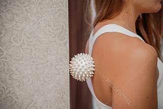 Athletic slim caucasian woman doing thigh self-massage with a massage ball indoors. Self-isolating massage