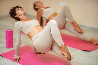 Fitness, pilates stretching exercises, a group of two attractive smiling mature women in beige sports clothes, train in