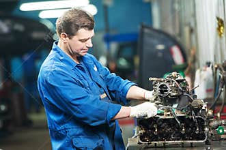 Auto mechanic at repair work with engine