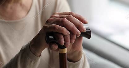 Close up view hands of older female holds walking stick