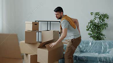 Tired guy bringing home heavy boxes then touching back suffering from backache during relocation
