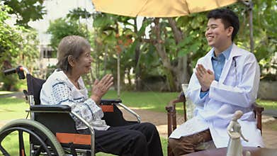 Thai doctor greeting wai senior patient in wheelchair