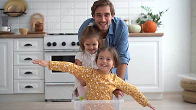 Happy father run push box with little cute children daughters ride inside