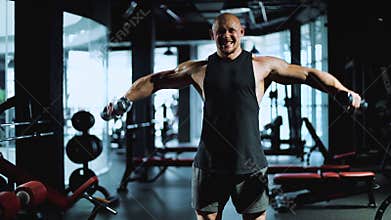 Man athlete trains with dumbbells in the sports gym. Fitness and workout motivation