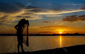 Silhouette of Thai Fisherman catching the fish in twilight  Beautiful Sunset in the sky with sky blue and orange light of the sun
