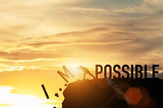 Businessman push impossible wording to possible wording on top of mountain with sunlight. Positive mindset concept