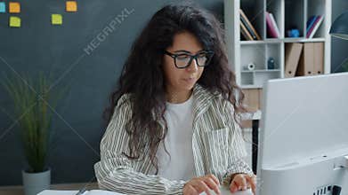 Happy young woman enjoying work results looking at computer screen clapping hands smiling in office