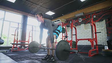 Handsome athletic man performing Bent-over row at gym