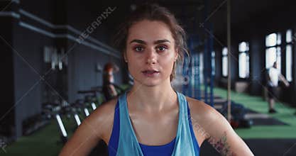 Zoom in portrait, serious young beautiful female athlete looking at camera, tired after intense workout at health club.