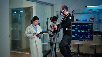 Sportsman with mask running on cross trainer in sports science laboratory