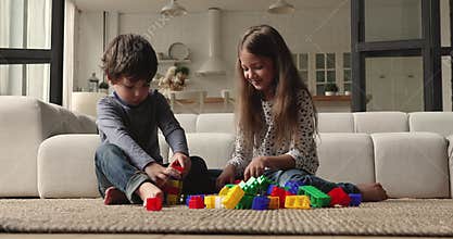Little kids play colorful plastic blocks at home