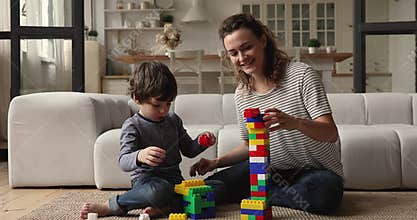 Mom teaches preschool son to build tower of colored block
