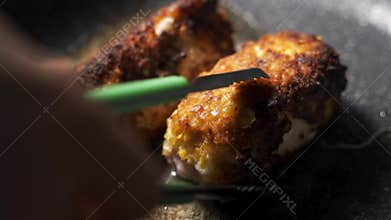 The cook turns the fried schnitzel on the other side. Cordon Bleu are grilled in a frying pan