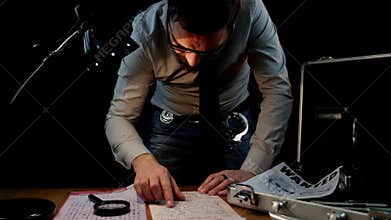 Detective standing with eyeglasses while examining documents of the Zodiac serial killer case