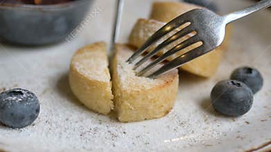 Metal fork and knife cutting cheese pancake piece in cafe