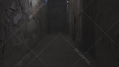 The camera glides over the floor in the hallway of an old dark, abandoned basement