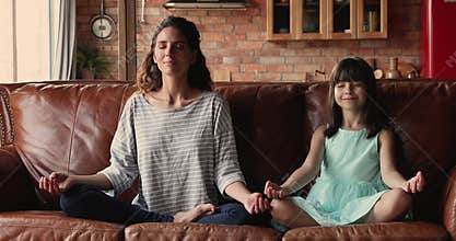 Young mom her daughter do meditation practice at home
