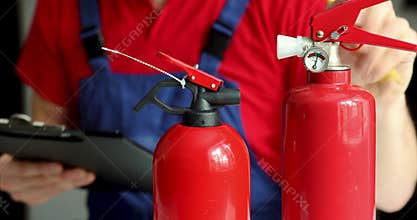 Fire safety and equipment maintenance service - man checking extinguisher condition and writing documents