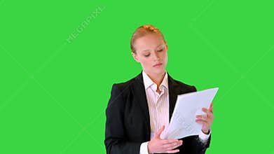 Young business woman looking through documents while walking on a Green Screen, Chroma Key.