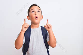 Beautiful student kid boy wearing backpack standing over isolated white background amazed and surprised looking up and pointing