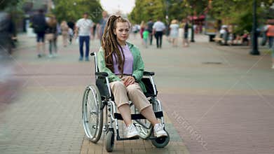 Time lapse of handicapped young lady with dreads in wheelchair among crowds of people walking by