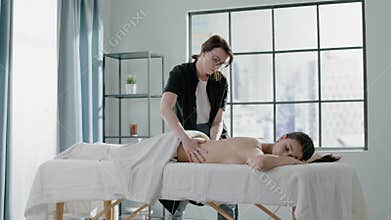 Therapist does back massage to woman patient in clinic