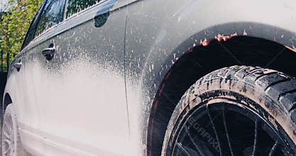 Car wash and auto detailing service, man covering car with foam using high pressure washer, close up video