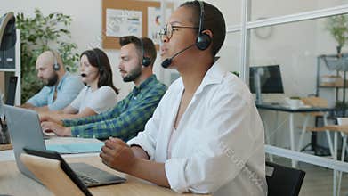 Mixed race group of emplyees are working in call center talking to customers using laptops busy with communication