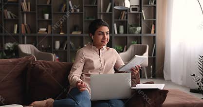Indian student makes assignment while sit on sofa with laptop