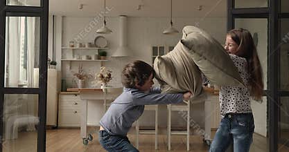 Crazy small child boy fighting pillows with laughing older sister.