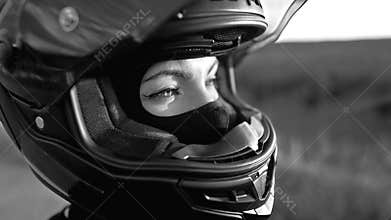 Black and white portrait of confident motorcyclist woman in closed motorcycle helmet. Young driver biker looking away