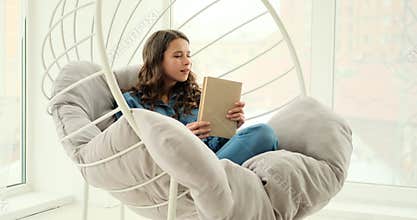 Beautiful woman reading book sitting on luxury chair